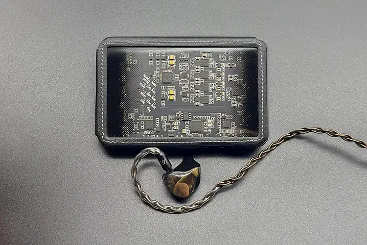 Noble Audio AGIS II shell and cable beside Questyle CMA18P