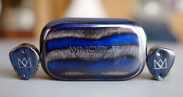 Noble FoKus Prestige Encore earbuds beside the charging cradle