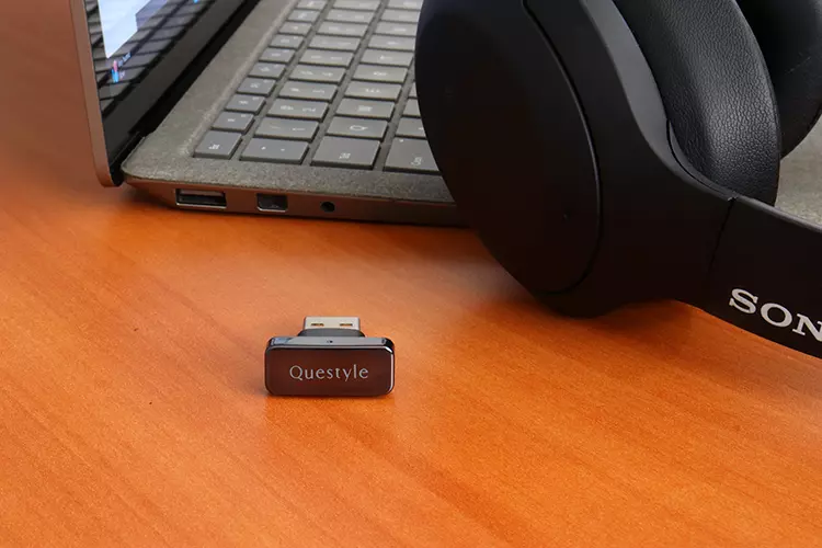 Questyle QCC Dongle Pro beside a laptop and Sony headphones